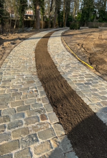 Aanleg van een gebogen oprit in kasseien met professionele fundering door tuinaannemer in Destelbergen